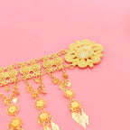 Gold floral filigree pendant with dangling charms on pink background, jewelry accessory