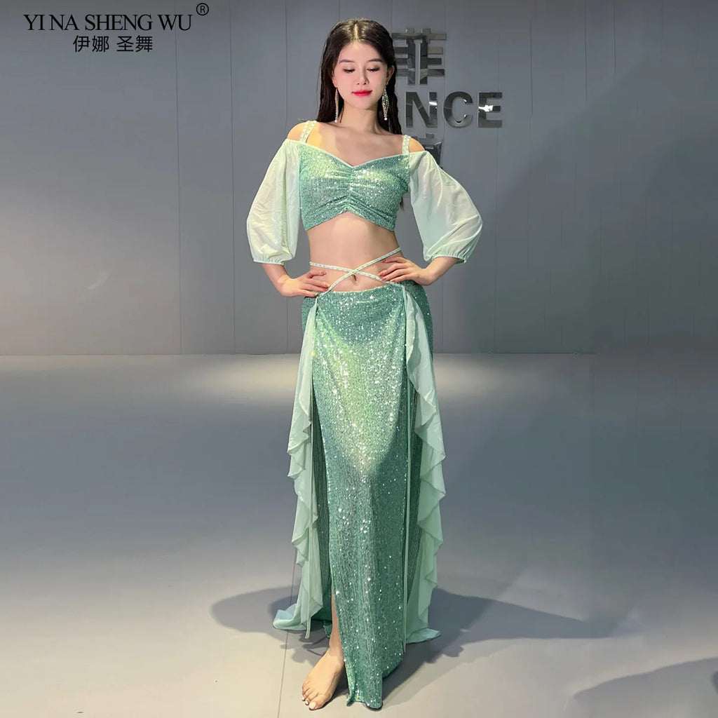 Woman wearing a mint green sequin belly dance costume with sheer sleeves and layered skirt.