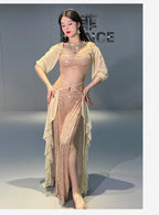 Woman in sparkly gold belly dance costume with sheer sleeves and layered skirt in studio