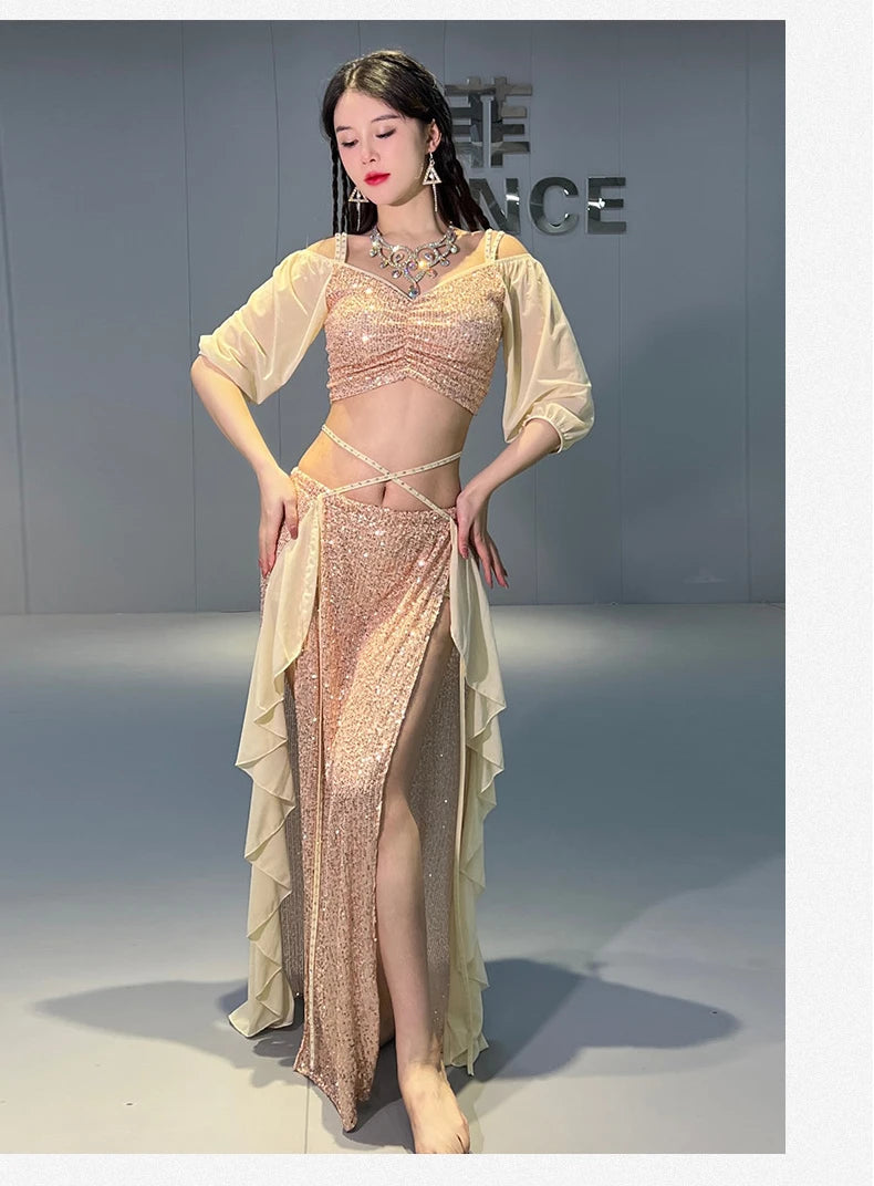 Woman in sparkly gold belly dance costume with sheer sleeves and layered skirt in studio