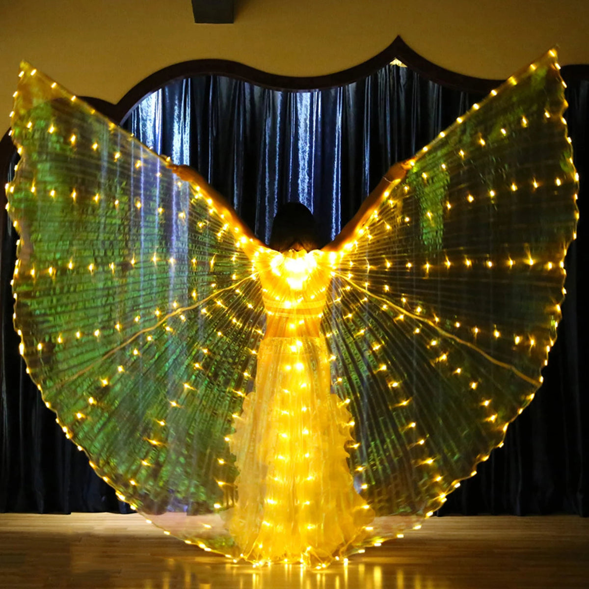 Person wearing illuminated LED light up wings costume on stage with glowing yellow lights
