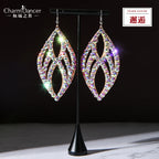 Rhinestone dangle earrings with leaf shape design displayed on a black stand