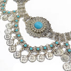 Boho silver coin necklace with turquoise beads and ornate central medallion on white background