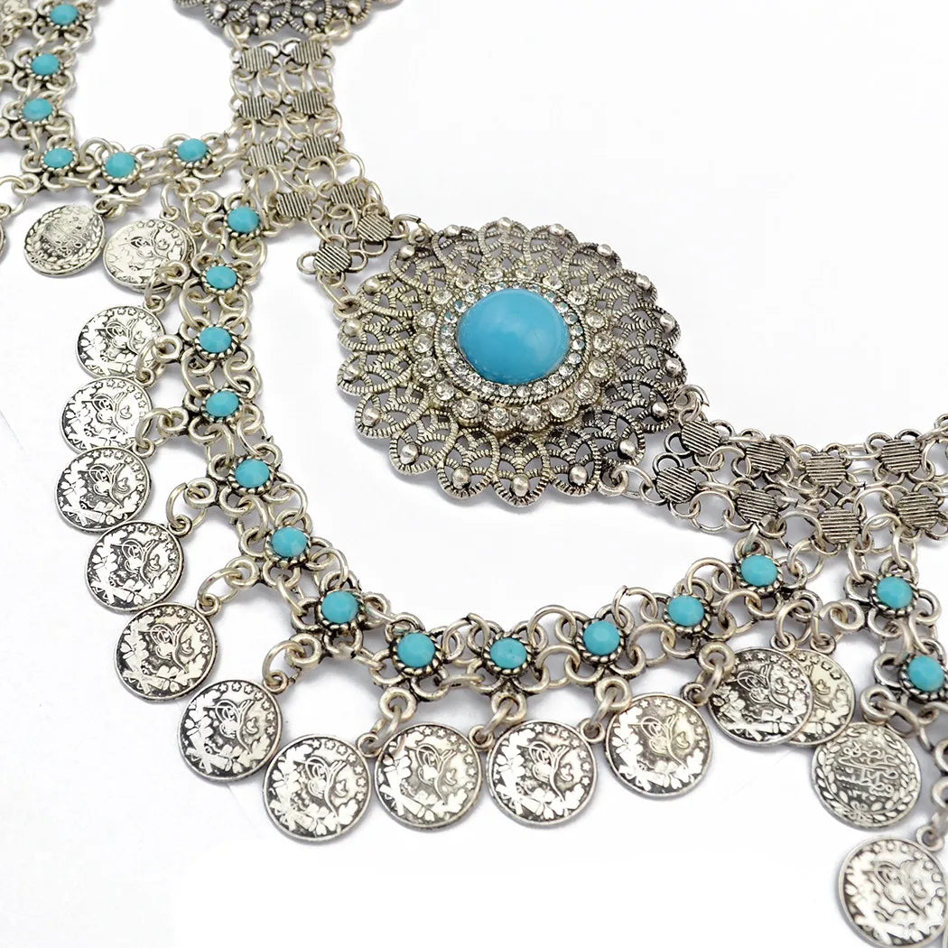 Boho silver coin necklace with turquoise beads and ornate central medallion on white background
