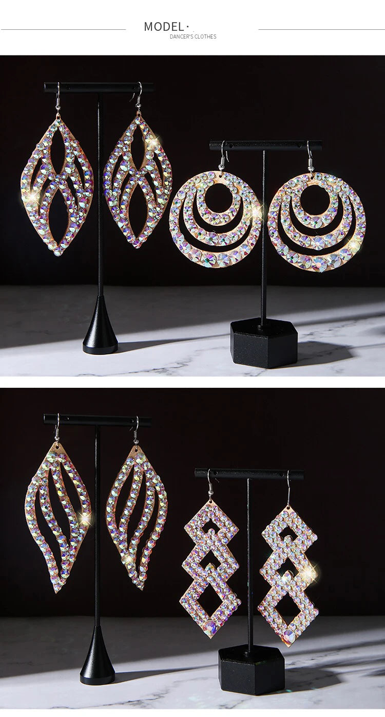 Four pairs of iridescent rhinestone statement earrings in geometric shapes on stands.