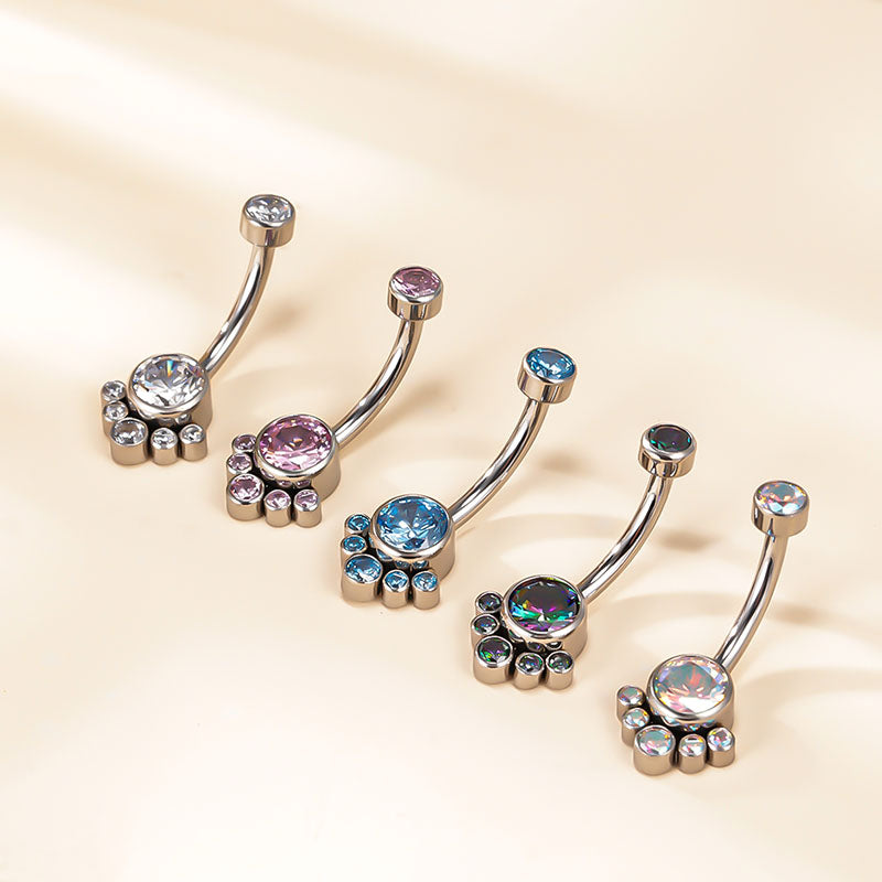 Set of jeweled belly button rings with colorful crystals on a beige background