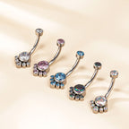 Set of jeweled belly button rings with colorful crystals on a beige background