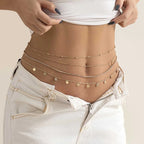 Layered gold waist chain jewelry on woman's bare waist with white denim jeans