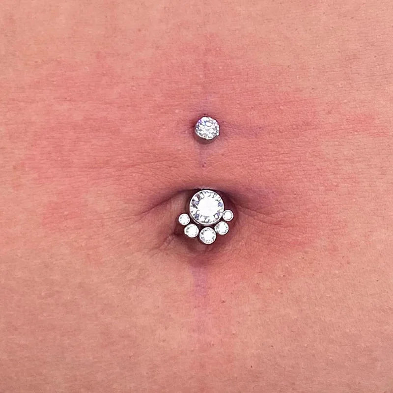 Belly button with double crystal jeweled piercings on skin, body jewelry closeup