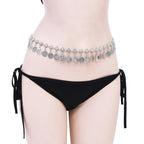 Woman wearing a black bikini bottom and a silver coin belly chain body jewelry