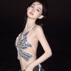 Woman wearing a silver sequin butterfly crop top with cutout sides, posing at night