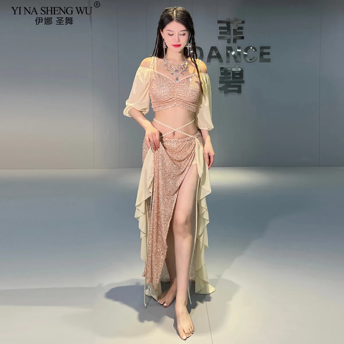 Woman in sparkling belly dance costume with slit skirt and off-shoulder sleeves indoors
