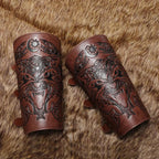 Pair of brown leather bracers with engraved wolf and Nordic designs on fur background