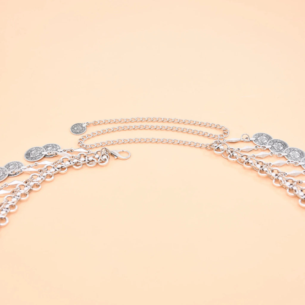 Silver chain belt with coin pendants on peach background