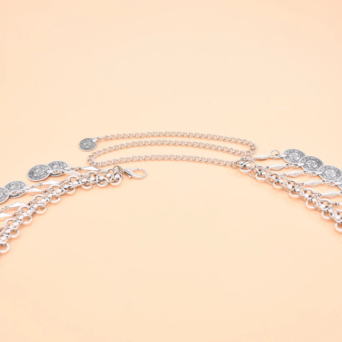 Silver chain belt with coin pendants on peach background