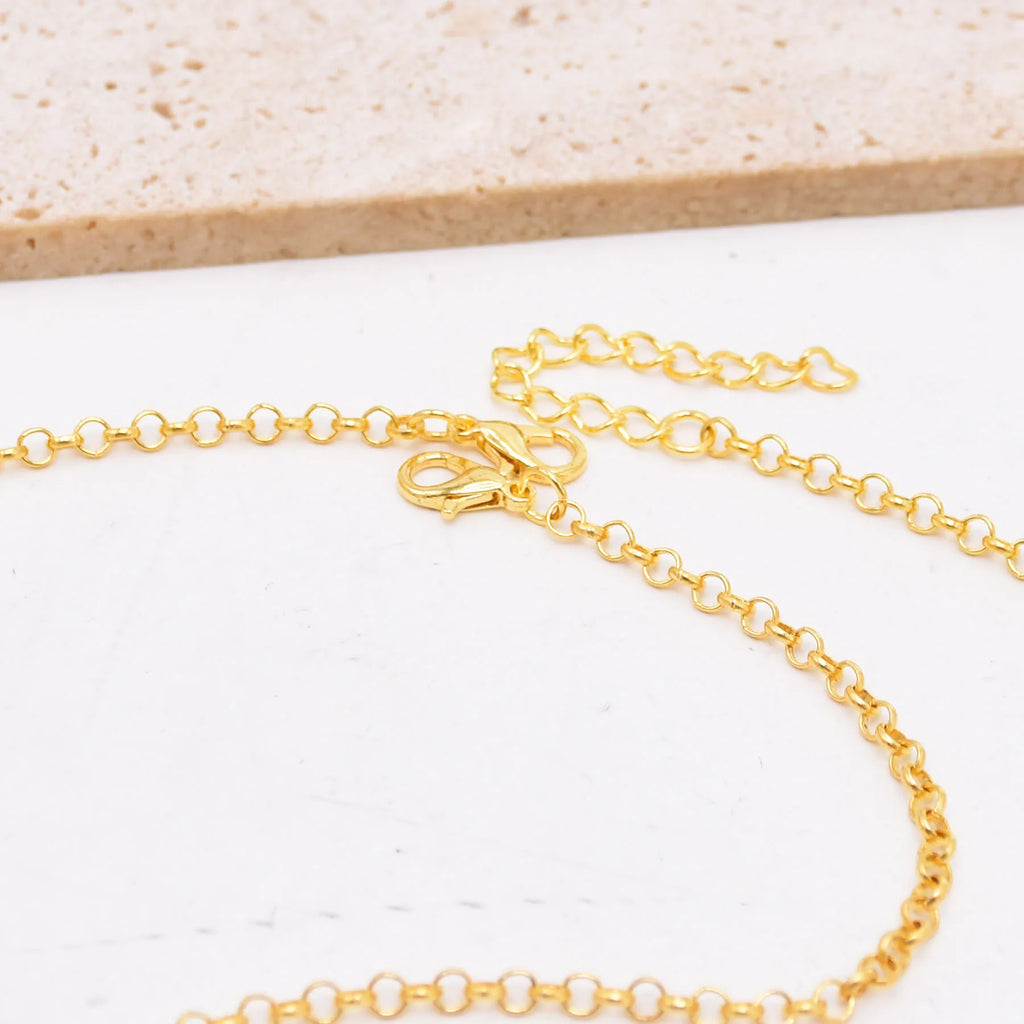 Gold chain necklace with lobster clasp on white stone background