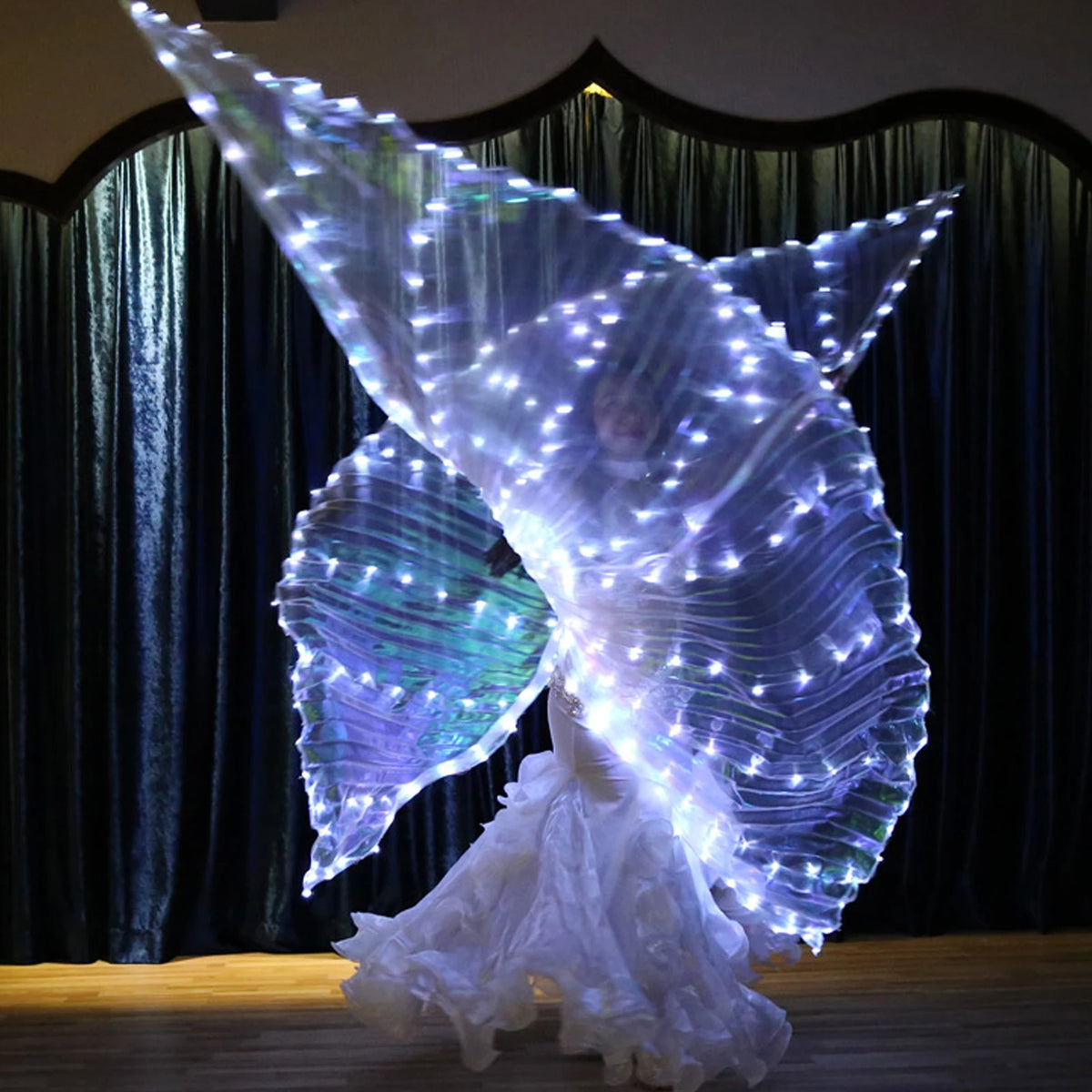 Dancer performing with LED light up wings and flowing white costume on stage