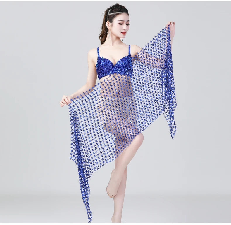 Woman modeling a blue sequin mesh wrap skirt and matching bra, standing on one leg.