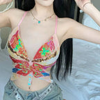 Woman wearing a colorful sequin butterfly crop top with spaghetti straps and gray denim jeans