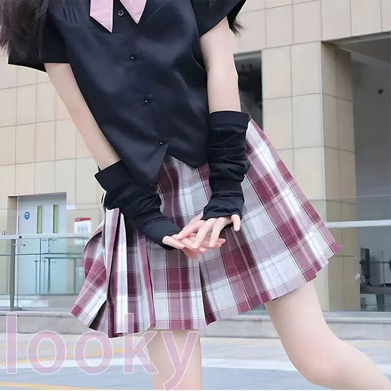 Person wearing pink plaid pleated skirt and black short-sleeve shirt outdoors