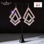 Pair of geometric rhinestone dangle earrings with gold-tone frames on a display stand