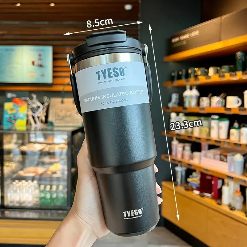 Black TYESO vacuum insulated bottle, 900ml, held in hand at a cafe with product dimensions shown.