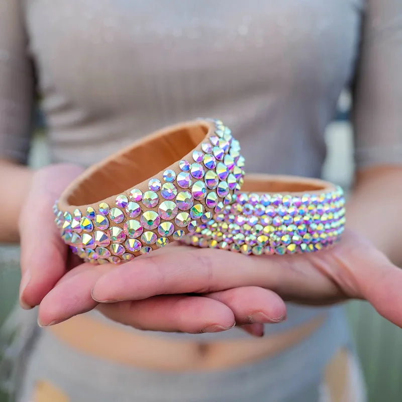 Hands holding two sparkly rhinestone headbands with iridescent crystal embellishments