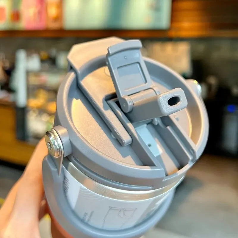 Close-up of gray insulated travel mug lid with drinking spout and flip-top opening