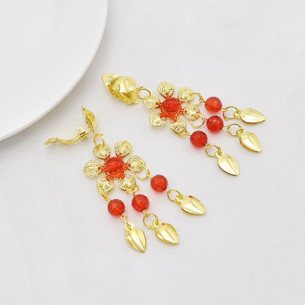 Gold floral dangle earrings with red beads and leaf charms on white background