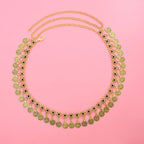 Gold coin statement necklace with black floral accents on a pink background