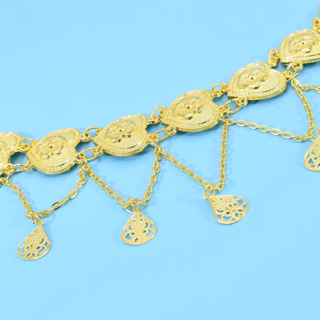 Gold heart charm bracelet with intricate floral designs on blue background