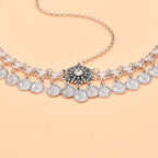 Silver coin charm necklace with floral centerpiece on light peach background
