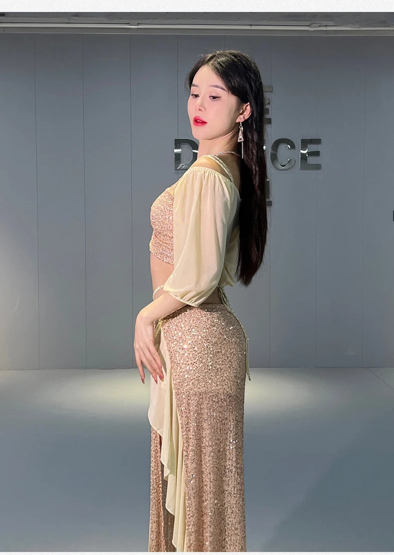 Woman in sparkling sequin dance outfit with sheer sleeves posing in dance studio