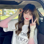 Woman in car wearing gradient long-sleeve top, making peace sign and smiling