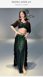 Woman modeling a sparkly green sequin belly dance costume with black chiffon wrap and large earrings