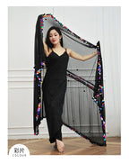 Woman in black sequin dress posing with sheer shawl decorated with colorful sequins indoors