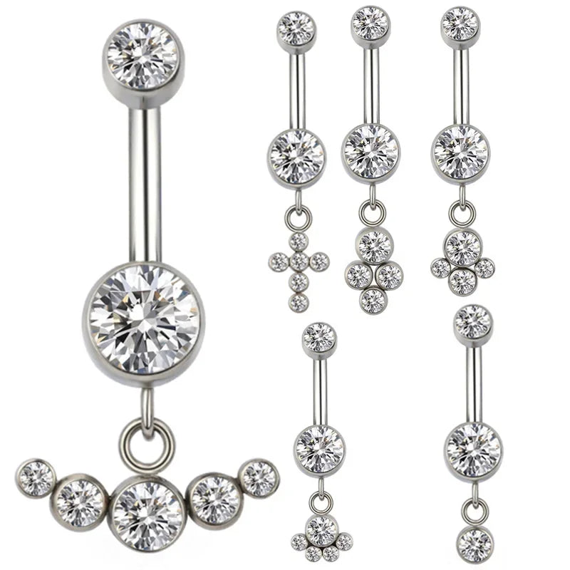 Multiple silver belly button rings with clear crystal dangle designs on white background