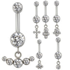 Multiple silver belly button rings with clear crystal dangle designs on white background