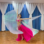 Woman performing in pink belly dance costume with iridescent wings indoors