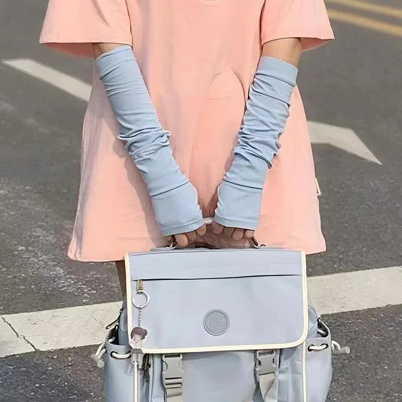 Person wearing blue arm sleeves and holding a light blue messenger bag outdoors