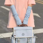 Person wearing blue arm sleeves and holding a light blue messenger bag outdoors