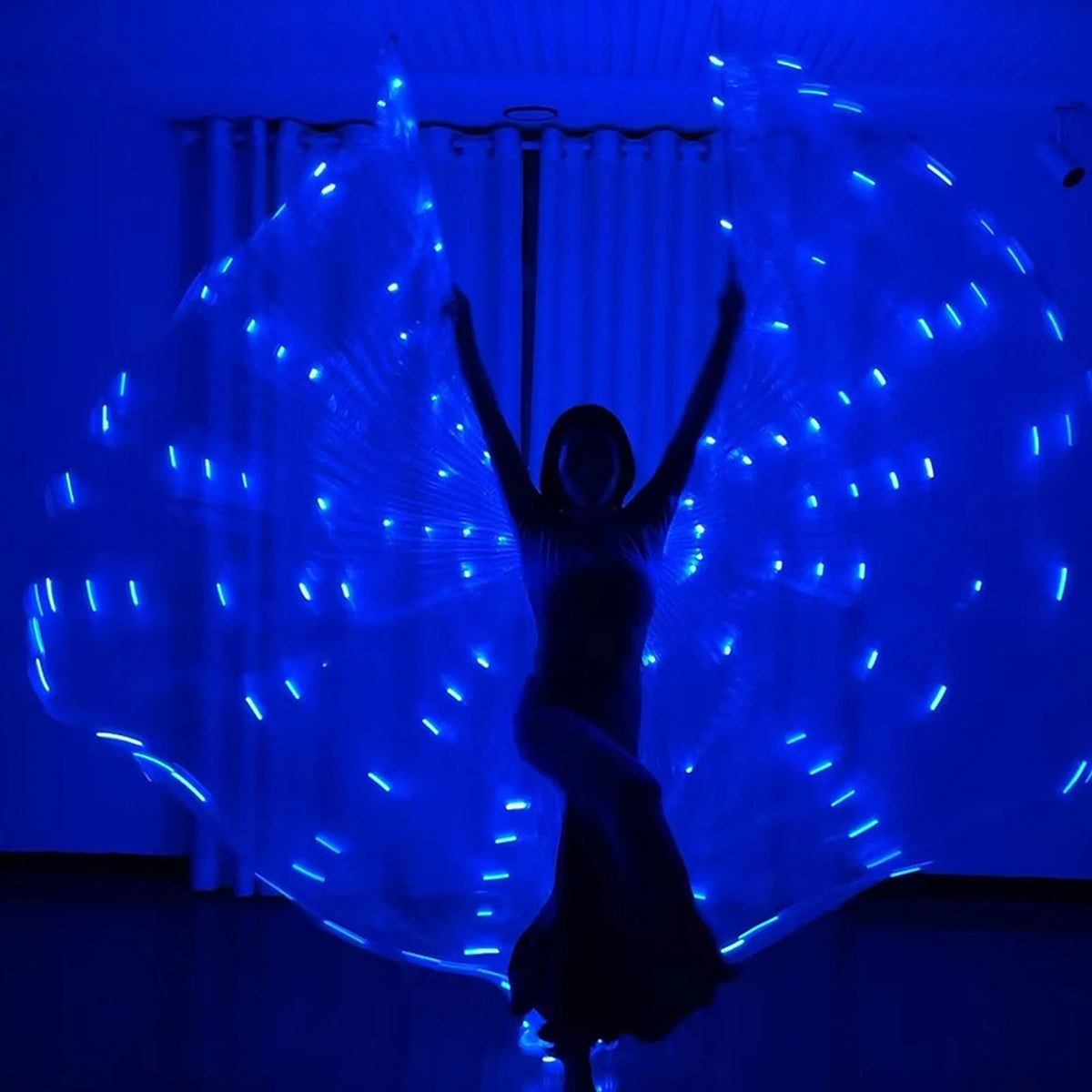 Dancer performing indoors with blue LED light up wings in a dark room.