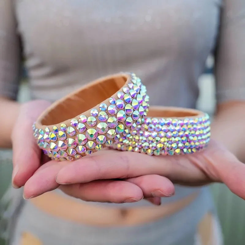 Hands holding two sparkling rhinestone-studded bangle bracelets, iridescent fashion accessories