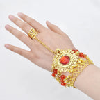 Hand wearing gold chain bracelet ring with red gemstone and decorative beads