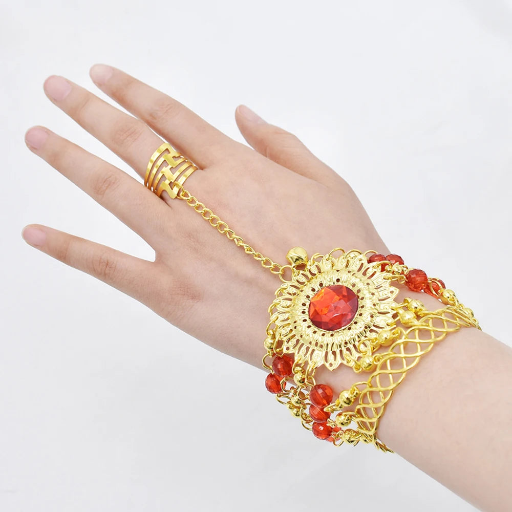 Hand wearing gold chain bracelet ring with red gemstone and decorative beads