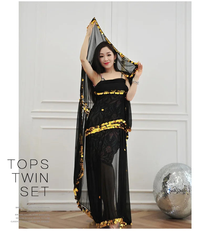 Woman in a black sheer dance costume with gold sequins, standing indoors near a silver ball